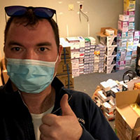 Man giving thumbs up with donations in background